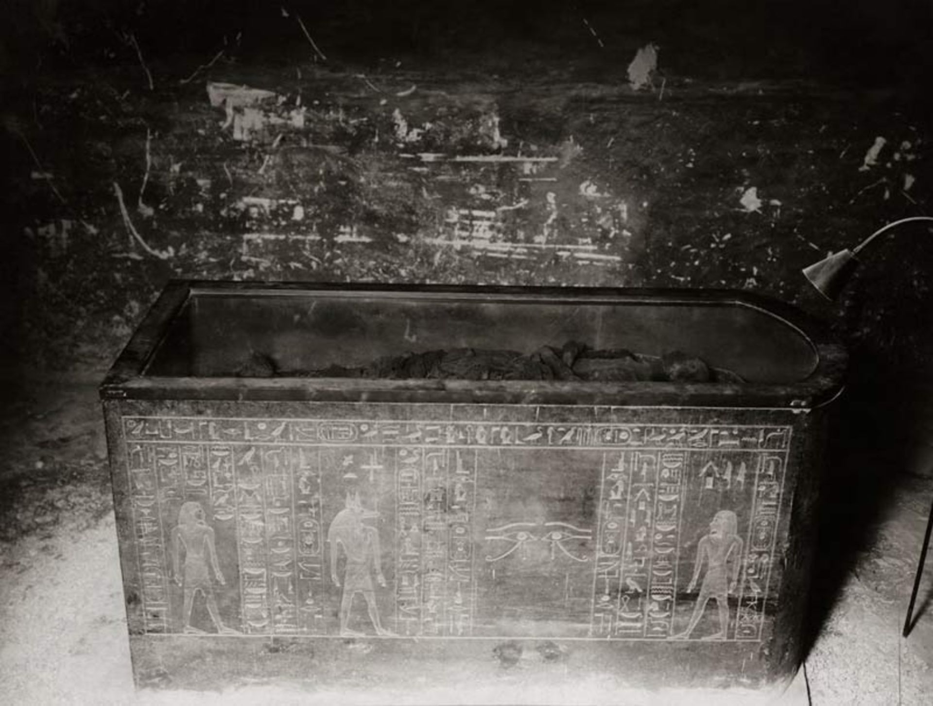 Opened stone coffin of Tutankhamun with hieroglyphic motifs and protective figures and mummy inside