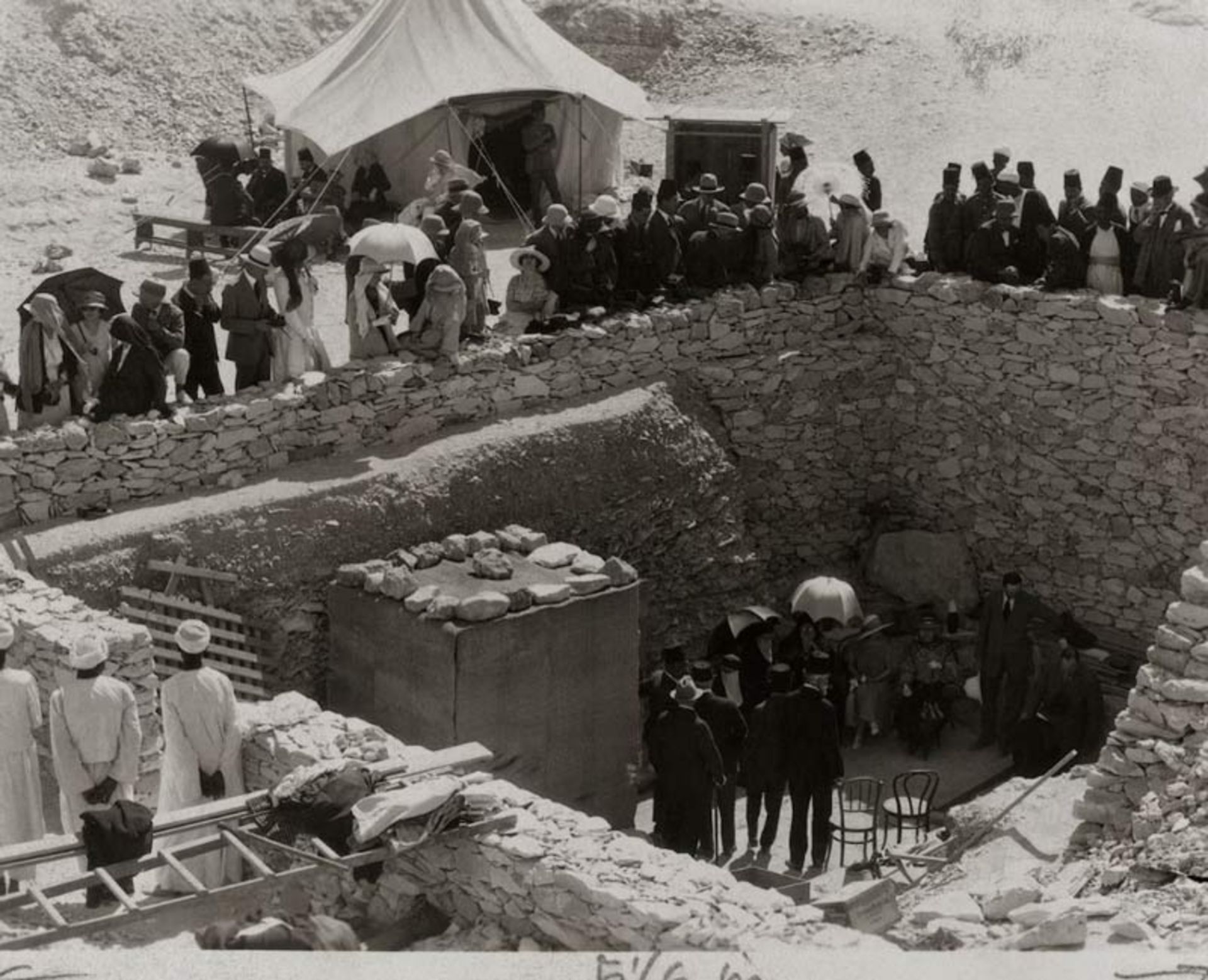 Black and white view of the crowd of spectators on top of the stone walls of the excavation site 