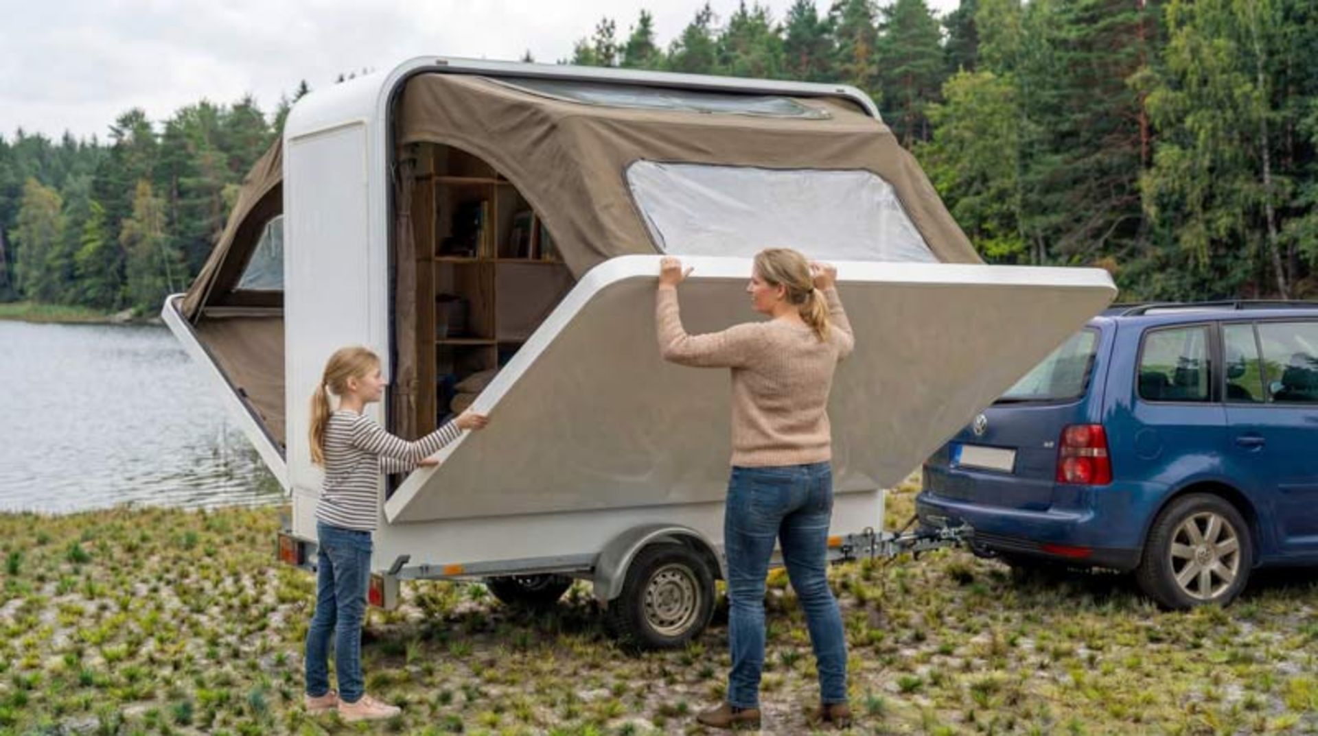 A young woman and girl manually opening one of the white side walls of the room