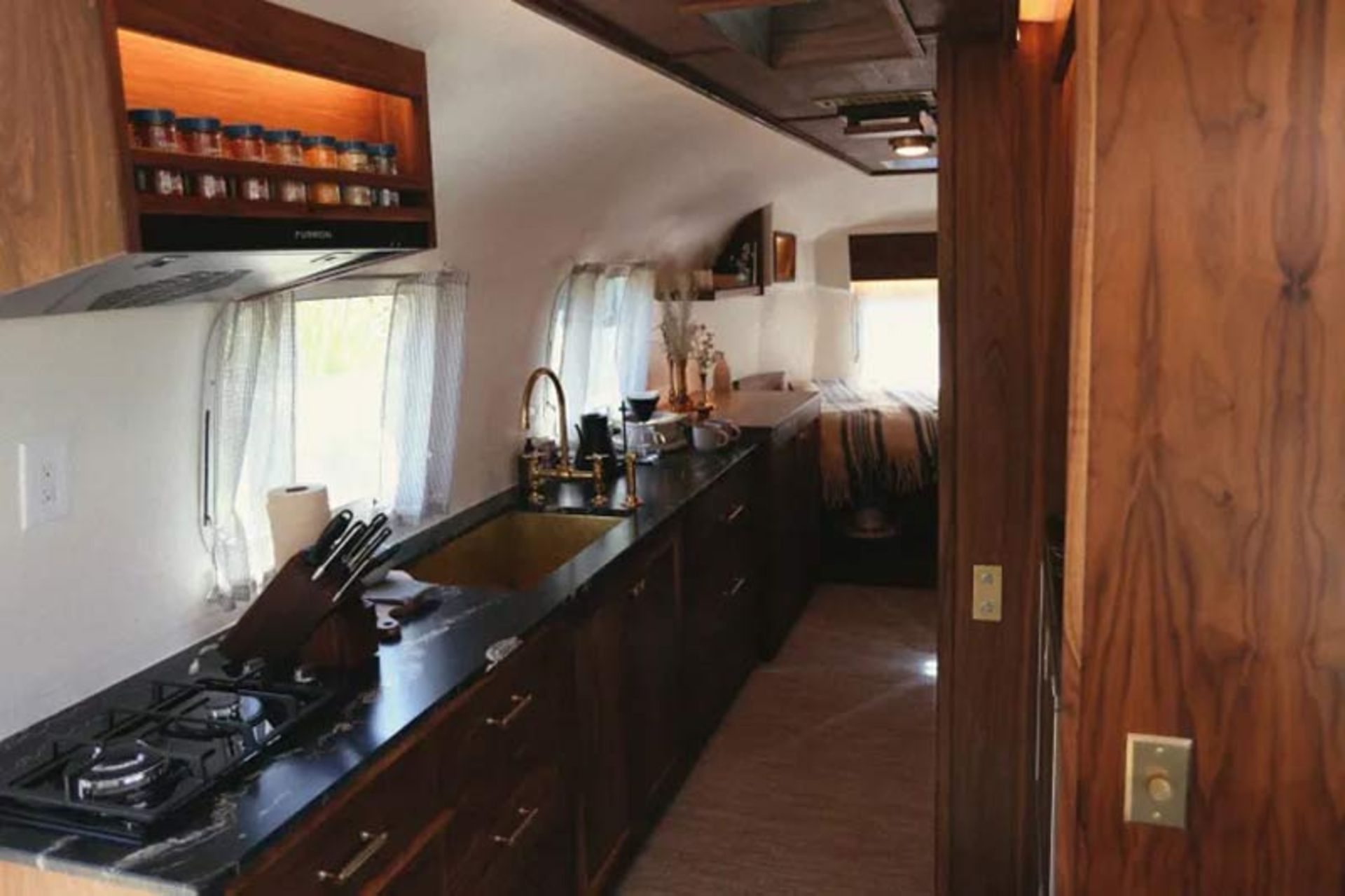 Linear layout of caravan kitchen with walnut cabinets and modern gas stove