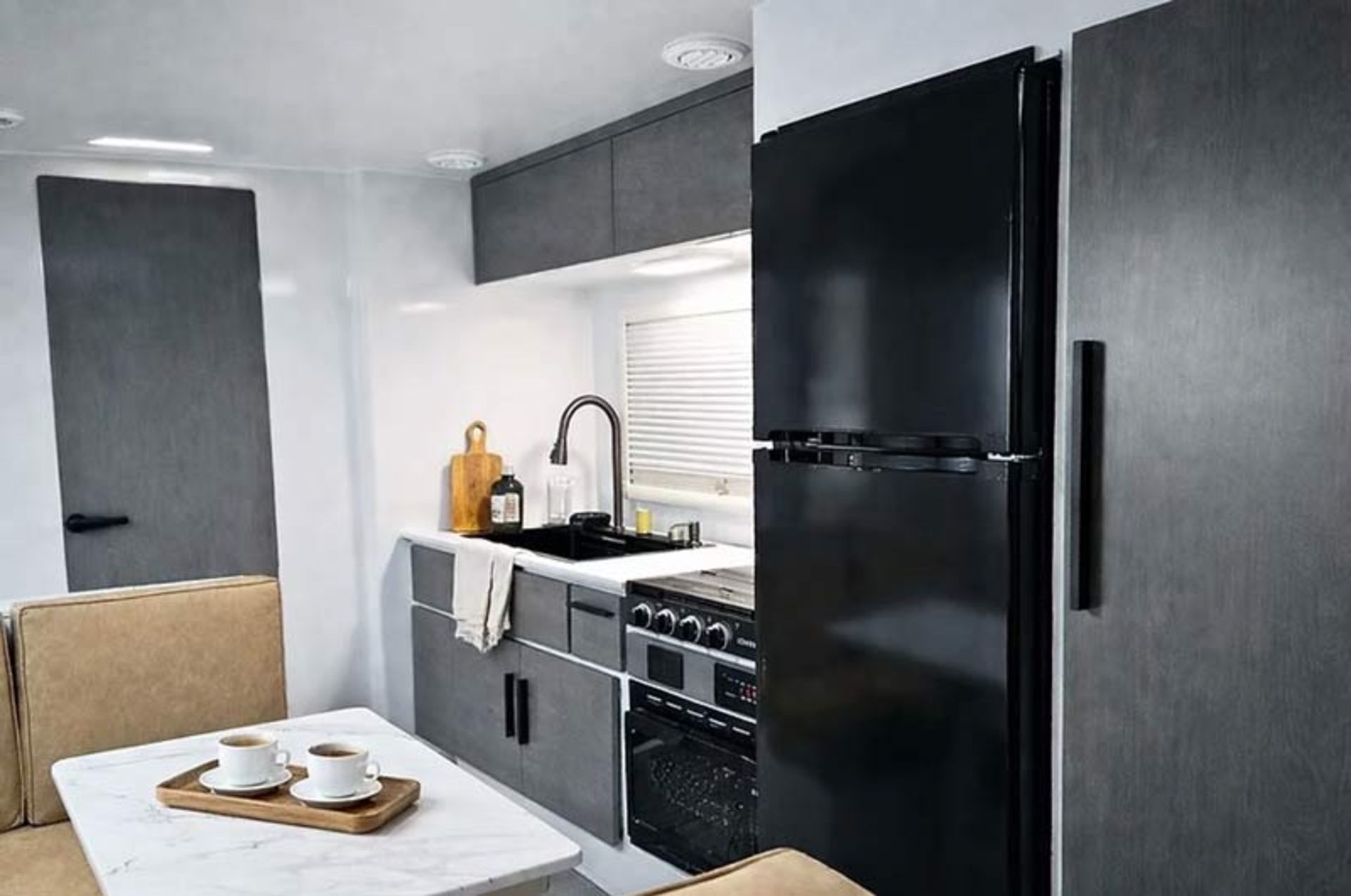 Modern and minimal interior design of a luxury room with gray cabinets and a large black refrigerator