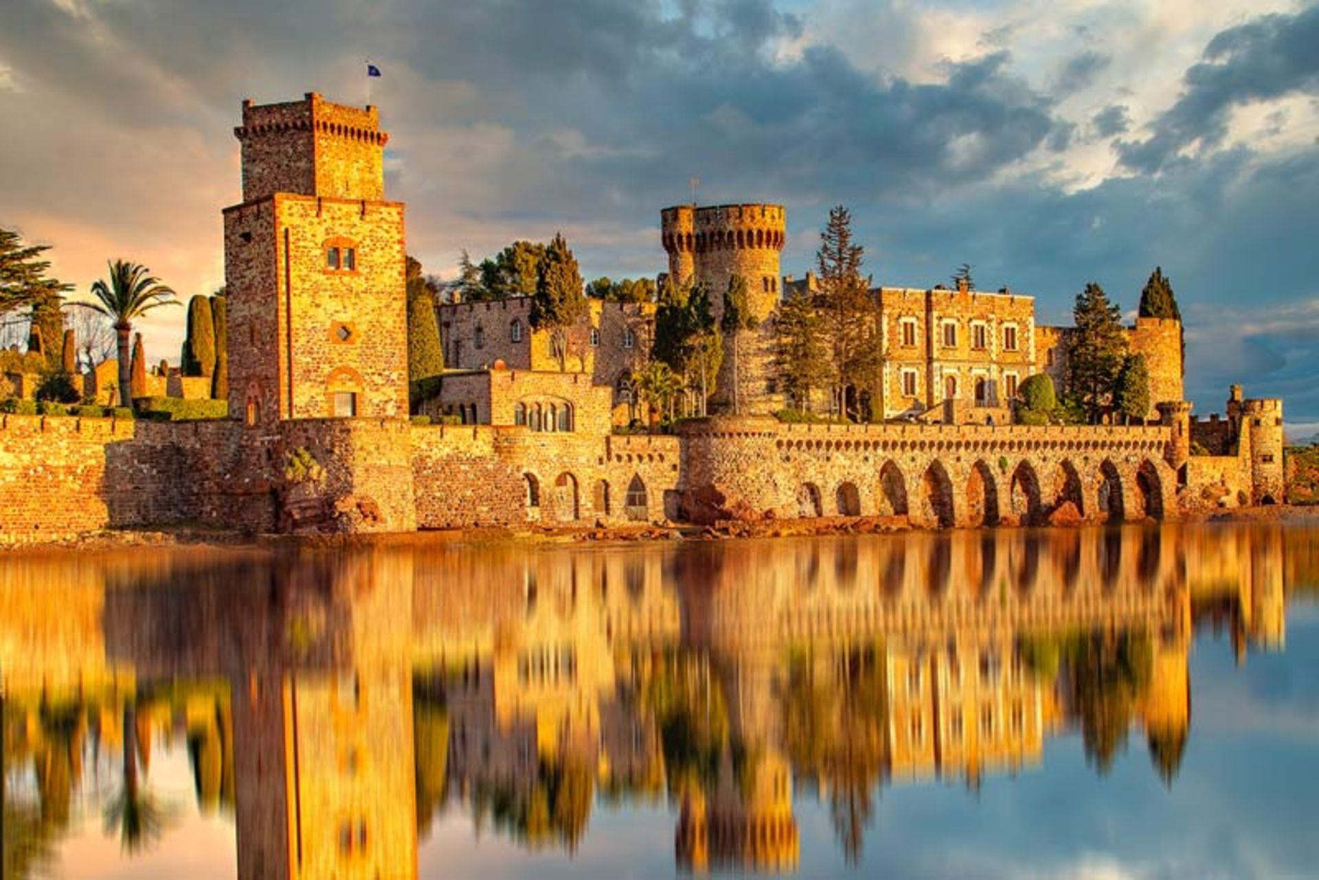 View of the stone castle of La Napolese in Mandelieu, France with a stunning reflection in the water at sunset