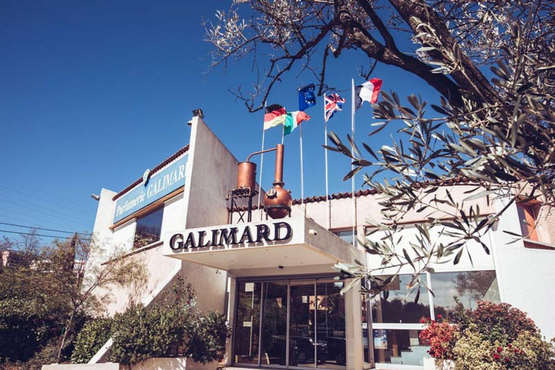 Entrance view of Gallimard perfumery building in Grasse, France with raised flags