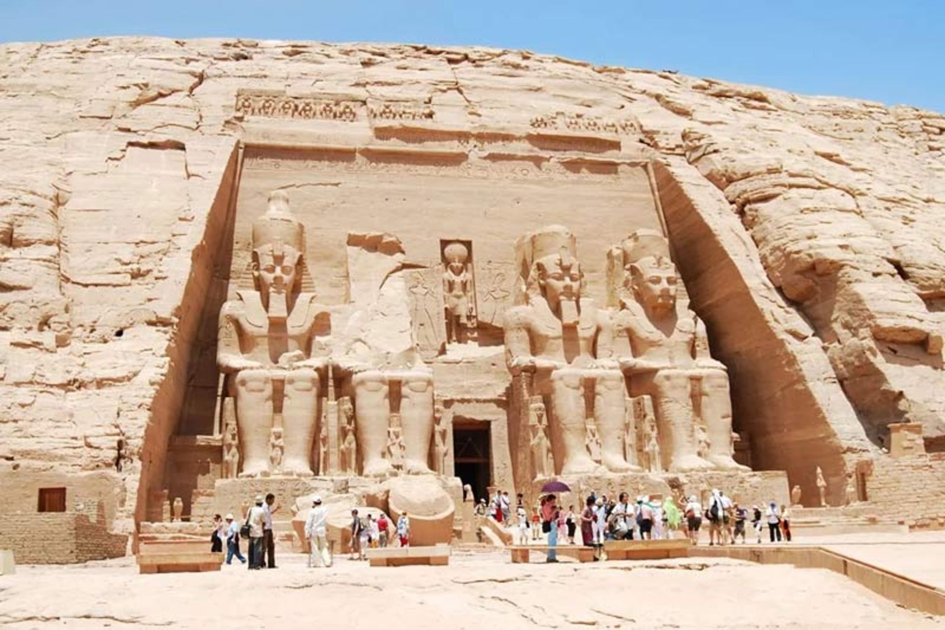 Entrance view of Abu Simbel Temple with giant statues of Ramses II and the presence of tourists