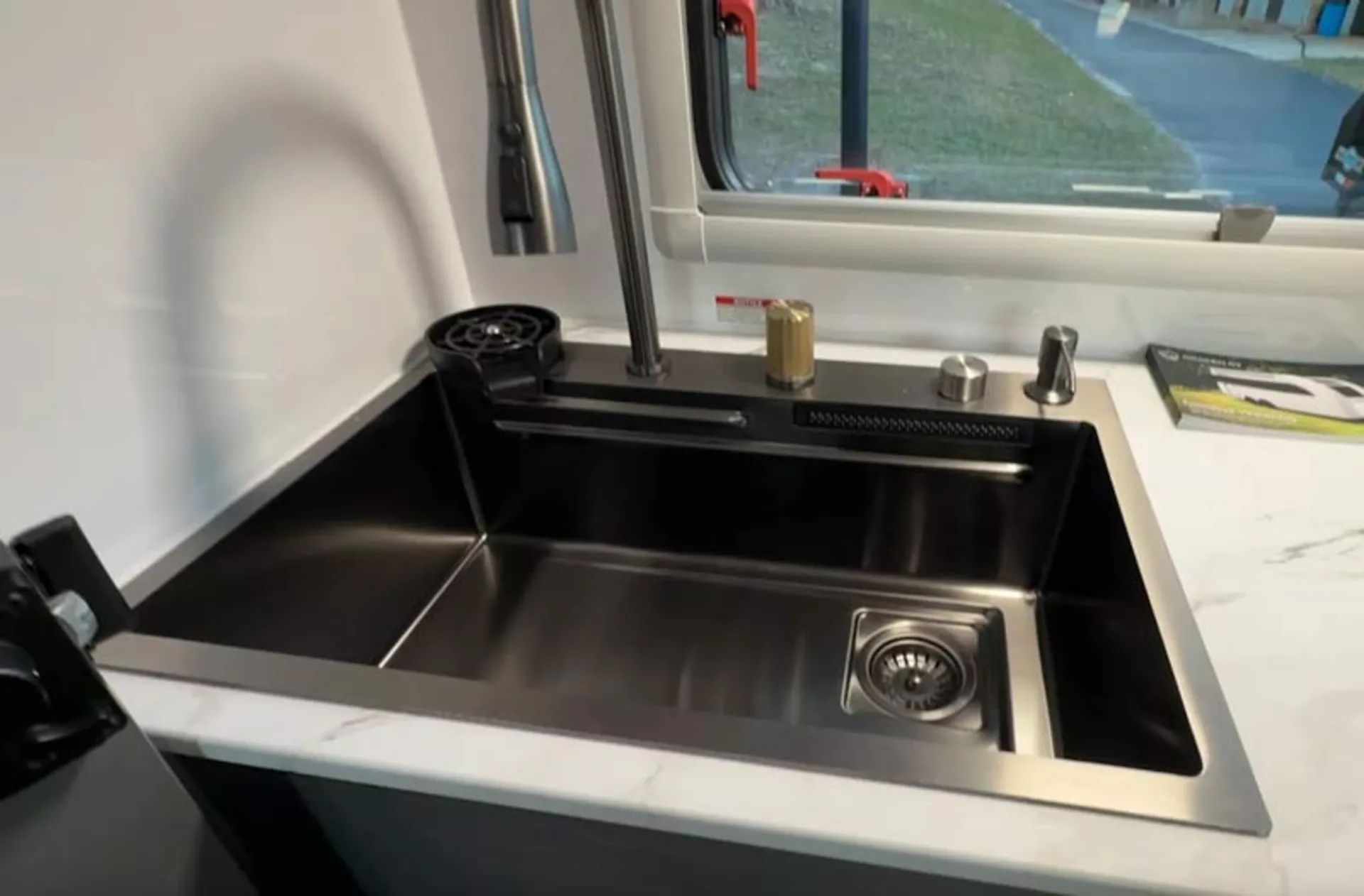 A close-up view of a stainless steel sink and modern faucets in the kitchen of a travel cabin